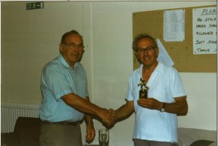 Photograph of Stan receiving the 1996 trophy from the 1995 champion