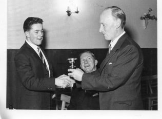 Peter receives a prize from Chairman Bert Ely. Roy Peglar looks on.